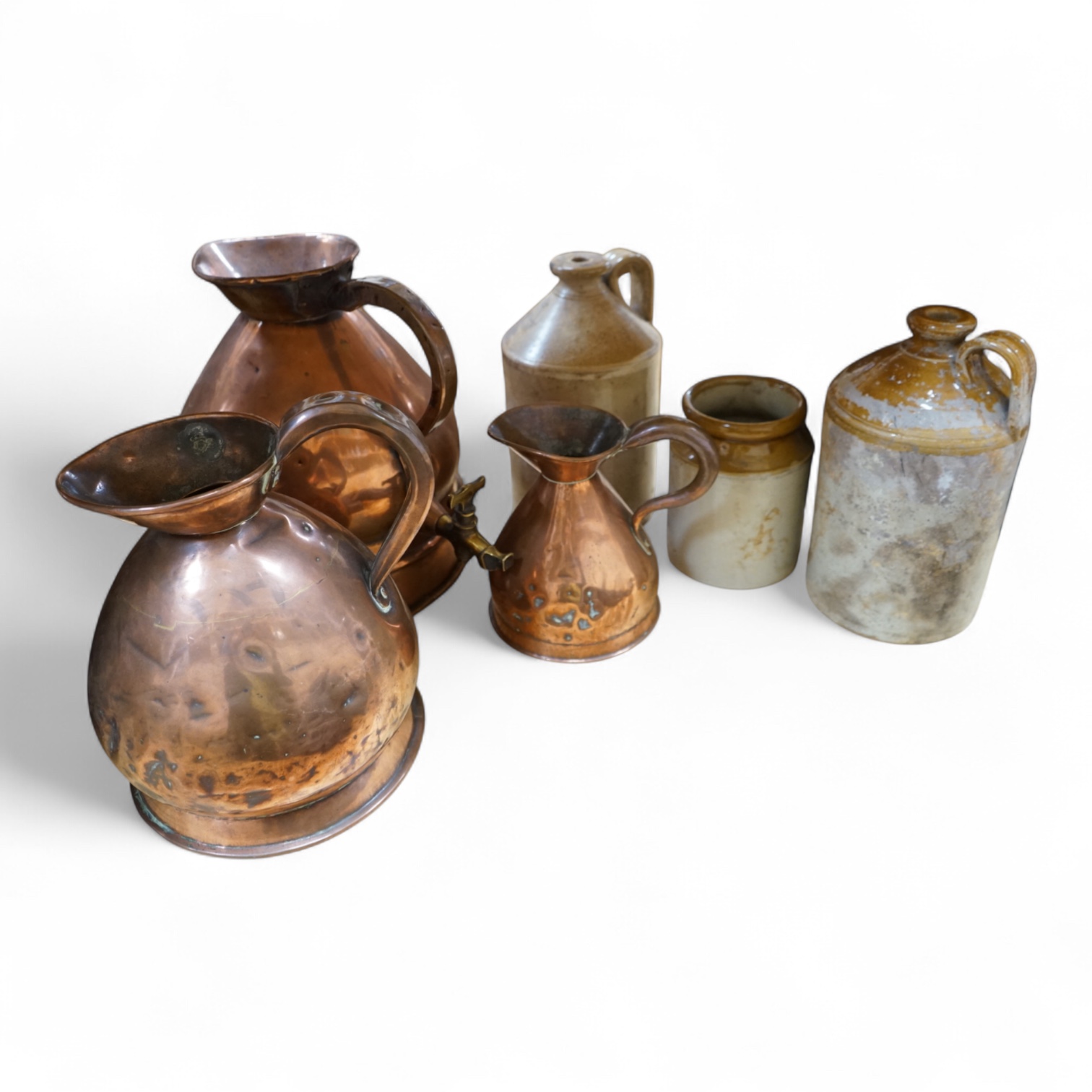 Three graduated copper haystack measures, H 39cm x W 40cm (inc spout), H 35cm x 25cm and H25cm x 18cm, Three stoneware jars H 32cm x W 20cm (two jars), H 20cm x W 16cm (1 jar)